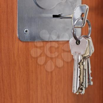 bunch of keys in keyhole of wooden door close up