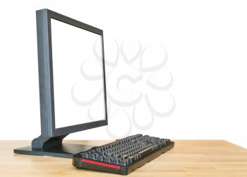 side view of black computer display with cut out screen and keyboard on wooden table isolated on white background