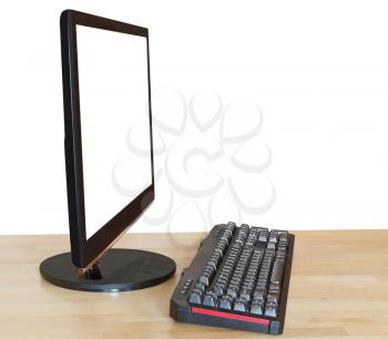 side view of computer black widescreen display with cutout screen and keyboard on wood table isolated on white background