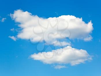 two fluffy white clouds in blue summer sky