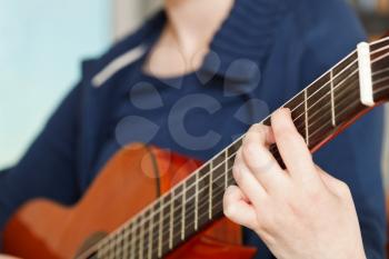 girl plays on modern acoustic guitar close up