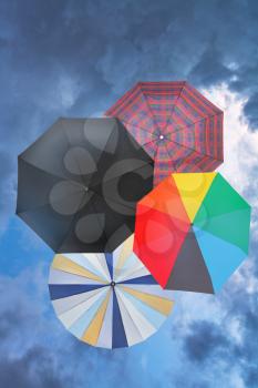 four open umbrellas with blue rainy clouds background
