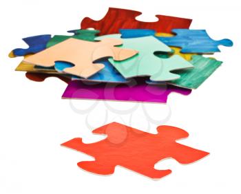 separate red puzzle piece in front of pile of jigsaw puzzles isolated on white background