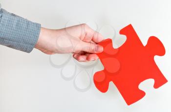 red puzzle piece in female hand on grey background