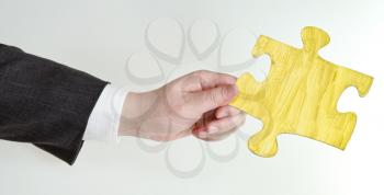 yellow painted puzzle piece in male hand on grey background