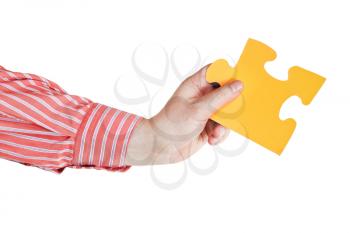 male hand holding big yellow paper puzzle piece isolated on white background