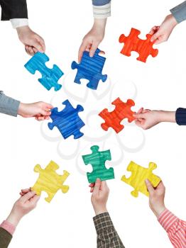 set of different puzzle pieces in people hands in circle isolated on white background