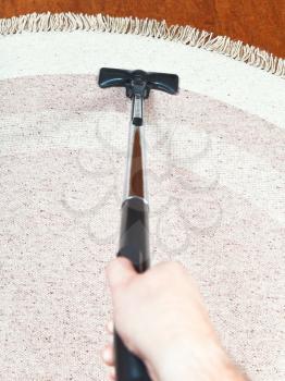man cleans a carpet with hoover at home