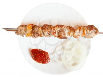 top view of skewer with lamb shish kebab on white plate isolated on white background