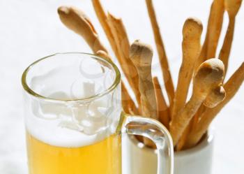 mug of beer and bread sticks close up on table at outdoor restaurant