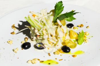 cold appetizer - Waldorf salad from apple, orange, celery on white plate at outdoor restaurant