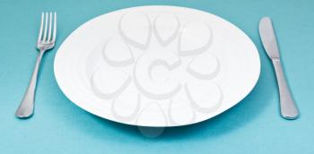 empty white plate with fork and knife on green background
