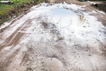 country road with rainy puddles in spring day