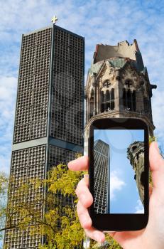 travel concept - tourist taking photo of kaiser wilhelm memorial church on mobile gadget in Berlin, Germany