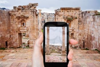 travel concept - tourist taking photo of ancient town Gerasa and modern city Jerash in Jordan on mobile gadget