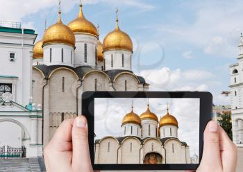 travel concept - tourist taking photo of Cathedral of the Dormition in Moscow Kremlin on mobile gadget, Russia