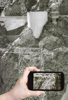 travel concept - tourist taking photo of power line of Hoover Dam on mobile gadget, USA