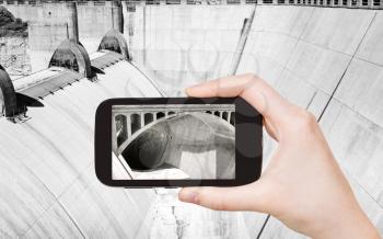 travel concept - tourist taking photo of Hoover Dam on mobile gadget, USA