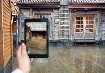 travel concept - tourist taking photo of wooden pavement in rain, Bergen, Norway of on mobile gadget
