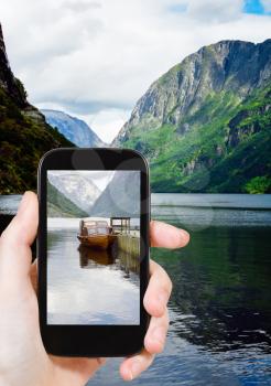 travel concept - tourist taking photo of fjord in Norway on mobile gadget