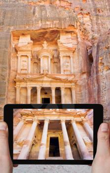 travel concept - tourist taking photo of Treasury Monument temple in ancient city Petra on mobile gadget, Jordan
