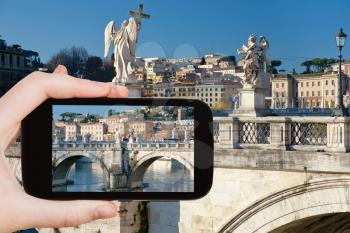 travel concept - tourist taking photo of Angel statues on bridge in Rome on mobile gadget, Italy