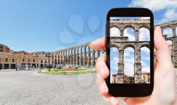 travel concept - tourist taking photo of ancient roman Aqueduct of Segovia, Spain on mobile gadget