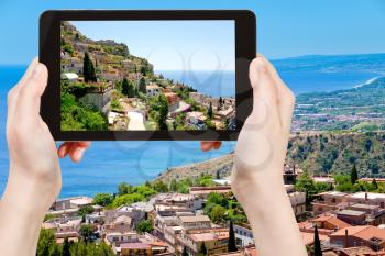 travel concept - tourist taking photo town Taormina from Castelmola, Sicily, Italy of on mobile gadget