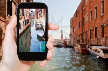 travel concept - tourist taking photo of Canal and bridge in Venice, Italy on mobile gadget