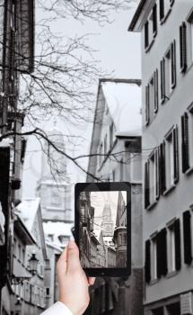 travel concept - tourist taking photo of Grossmunster church and street in Zurich in winter on mobile gadget, Switherland