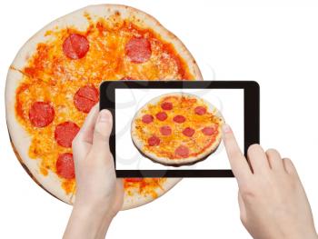 photographing food concept - tourist takes picture of italian pizza with spicy salami on smartphone, Italy