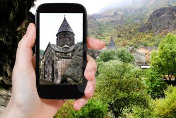 travel concept - tourist takes picture of Katoghiken church of medieval geghard monastery in Armenia on smartphone,