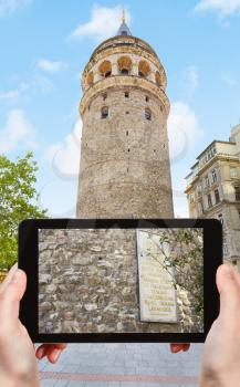 travel concept - tourist takes picture of medieval Galata tower in Istanbul, Turkey on smartphone,