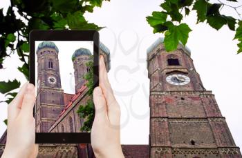 travel concept - tourist takes picture of two tower Frauenkirche cathedral in Munich on smartphone, Germany