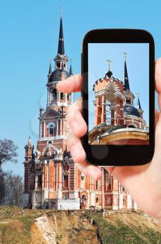 travel concept - tourist takes picture of New Nikolsky Cathedral in Mozhaysk Kremlin, Moscow Regoin, Russia on smartphone,
