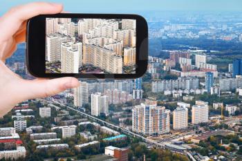 travel concept - tourist takes picture of block of modern houses in Moscow autumn day on smartphone,