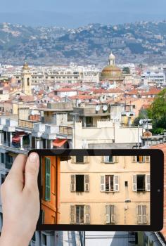 travel concept - tourist takes picture of house in old town of Nice, France on smartphone