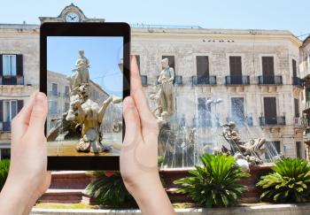 travel concept - tourist takes picture of fountain on Piazza Archimede in Syracuse, Sicily, Italy on tablet pc