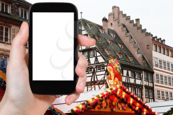 travel concept - tourist photograph Christmas market in medieval european town Strasbourg on smartphone with cut out screen with blank place for advertising logo
