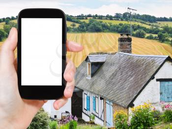 travel concept - tourist photograph peasant farm and harvested field in Normandy, France on tablet pc with cut out screen with blank place for advertising logo