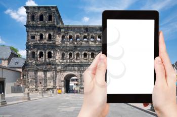 travel concept - tourist photograph view on Porta Nigra (antique Roman gate) in Trier, Germany on tablet pc with cut out screen with blank place for advertising logo