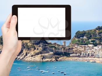 travel concept - tourist photograph urban beach and Vila Vella monument in town Tossa de Mar, Costa Brava, Catalonia, Spain on tablet pc with cut out screen with blank place for advertising logo