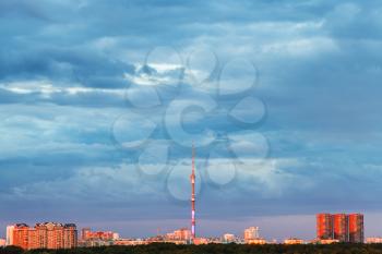 blue rainy clouds over illuminated by pink sunset light city with tv tower