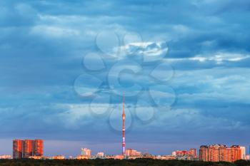 dense blue evening clouds over illuminated by pink sunset light city with tv tower