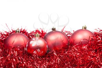four red Christmas balls and tinsel isolated on white background
