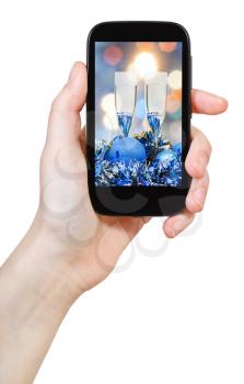 hand holds cellular phone with Christmas still life on screen isolated on white background