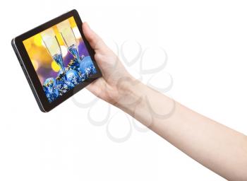 hand holds tablet pc with Christmas still life on screen isolated on white background