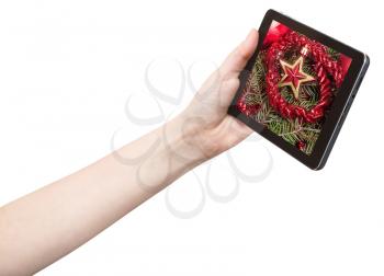 hand holds tablet pc with red star and tinsel on screen isolated on white background