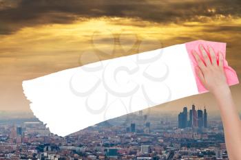 ecology concept - hand deletes smog sky over city by pink rag from image and white empty copy space are appearing