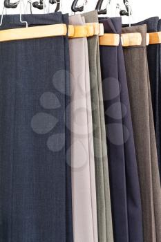 various woolen trousers on hangers in tailoring atelier close up
